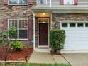 Close-up of a home's front entrance with stone veneer, a dark front door and neat landscaping at 552 Stobhill Ln, Holly Springs, NC 27540