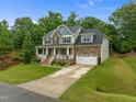 Charming two-story home with a welcoming front porch, manicured lawn, and attached two-car garage in a lovely community at 6949 Rex Rd, Holly Springs, NC 27540