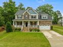 Charming two-story home with a welcoming front porch, manicured lawn, and attached two-car garage in a lovely community at 6949 Rex Rd, Holly Springs, NC 27540