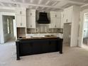 Unfinished kitchen featuring an island and white cabinets with a black range hood at 79 Oldham Estate Dr, Chapel Hill, NC 27517