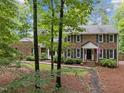 Charming brick home with black shutters, an American flag, and mature trees in the front yard at 102 Mel Oak Dr, Chapel Hill, NC 27516