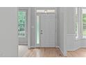 Bright entryway featuring a white front door with sidelight windows and hardwood flooring at 1208 Mossy Glade Cir, Apex, NC 27502