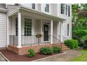 Inviting front porch with brick accents, black railing, and a decorative wreath on the front door at 1208 Mossy Glade Cir, Apex, NC 27502