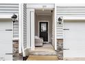 Inviting townhome entryway with neutral chair, gray siding, and a secure front door at 1213 Grenshaw Dr, Morrisville, NC 27560