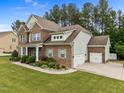 Side view of a brick home, featuring an attached two-car garage and well-kept landscaping at 21 Botanical Way, Pittsboro, NC 27312