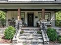 Inviting front porch with stone pillars, wrought iron railing, and comfortable seating area at 2303 Byrd St, Raleigh, NC 27608