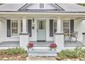 Inviting porch featuring painted brick columns, gray trim, seating, and a charming teal front door at 2418 Highland Ave, Durham, NC 27704