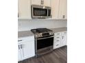 Close-up of a stainless steel gas range and microwave in a modern kitchen with white cabinets at 269 Hank Way, Angier, NC 27501