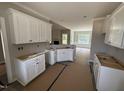 Partially assembled kitchen with white cabinets and view into a living room with a fireplace and lots of natural light at 2744 Rains Mill Rd, Princeton, NC 27569