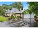 View of the home with a long driveway and attached garage, surrounded by mature trees and landscaping at 2805 Friendship Rd, Durham, NC 27705