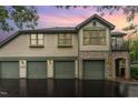 Townhouse exterior featuring multiple garage doors, stone accents, upper balcony, and decorative dormer under a twilight sky at 301 Presque Isle Ln, Chapel Hill, NC 27514