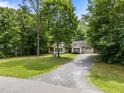 Ranch-style home with gravel driveway and manicured lawn surrounded by mature trees at 4508 Alice Dr, Oxford, NC 27565