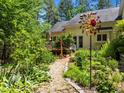 Lush backyard featuring a gravel path, decorative garden art, a wooden deck, and colorful greenery at 676 Whitehurst, Pittsboro, NC 27312