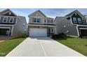 View of the new construction home with a two-car garage and stone accents, showing the lawn and driveway at 753 Swim Cave Ln, Wendell, NC 27591
