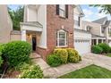Charming home featuring a brick facade, white siding, and an attached two-car garage with green bushes in front at 8013 Morrell Ln, Durham, NC 27713