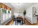 Elegant dining room with wallpapered accent wall, decorative molding, chandelier, and natural light at 102 W Hill Dr, Cary, NC 27519