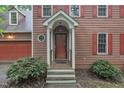 Inviting front entrance with a covered porch, red door, and meticulously maintained landscaping at 105 Trailwood Ct, Chapel Hill, NC 27516