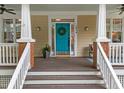 Inviting front porch featuring a bright blue door with wreath, white columns, and cozy outdoor space at 10579 Evergreen Spring Pl, Raleigh, NC 27614
