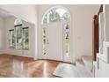 Bright foyer featuring hardwood floors, a white front door, and a carpeted staircase at 111 Catherwood Pl, Cary, NC 27518