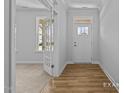 Inviting foyer featuring wood flooring, a white front door, and an adjacent room with carpeted floors at 112 Cultivator Ct, Angier, NC 27501