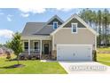 Inviting home showcasing stone accents, a cozy front porch, and an attached two-car garage at 112 Cultivator Ct, Angier, NC 27501