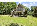 Inviting two-story home featuring a well-manicured lawn, trees, and a cozy covered front porch at 12636 Old Creedmoor Rd, Raleigh, NC 27613