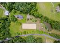 An aerial view displays a home with paddocks, a barn, a sand arena, and a small pond surrounded by mature trees at 12823 Summerwind Trl, Rougemont, NC 27572