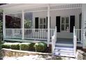 Inviting covered front porch with white railing, black shutters, and a charming entryway at 1300 Keynes Ct, Raleigh, NC 27615
