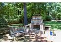 Custom stone outdoor fireplace with built-in seating and lush greenery at 1300 Keynes Ct, Raleigh, NC 27615