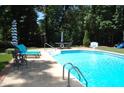 Sparkling in-ground pool with poolside seating, umbrellas, and a lush green surrounding landscape at 1300 Keynes Ct, Raleigh, NC 27615