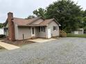 A beige home featuring a new roof, exterior doors, and gravel driveway at 1942 Brier Ln, Graham, NC 27253