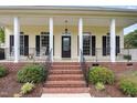 Inviting front porch with black railings, brick steps, and rocking chairs at 20 Wood Ibis Way, Louisburg, NC 27549