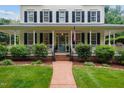 Classic home with a inviting front porch, featuring an American flag and manicured landscaping at 200 Cobblepoint Way, Holly Springs, NC 27540