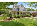 Beautifully landscaped home with a covered front porch, lush greenery, and classic architectural details at 200 Cobblepoint Way, Holly Springs, NC 27540