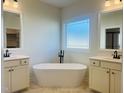 Bright bathroom featuring a soaking tub with modern faucet, double vanities, and natural light at 204 Seahawk Way, Zebulon, NC 27597