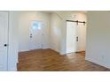 Inviting entryway with natural wood flooring, white trim, interior door, and a sliding barn door at 204 Seahawk Way, Zebulon, NC 27597