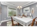 Dining room featuring neutral walls with white trim, elegant chandelier, and large windows at 352 Fire Opal Ln, Holly Springs, NC 27540