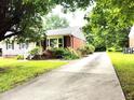 Single-story home with brick accents, a well-manicured lawn, and a long driveway at 404 Oakgrove Dr, Graham, NC 27253