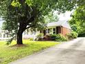Quaint single-story home with brick accents, a well-manicured lawn, and a long driveway at 404 Oakgrove Dr, Graham, NC 27253