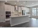 Modern kitchen boasts stainless appliances, island with pendant lighting, and sleek white cabinetry at 5028 Jowetts Walk Dr # 24, Cary, NC 27519