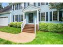 Charming blue two-story home with a brick front porch, lush landscaping, and a two-car garage at 5800 Heatherbrook Cir, Raleigh, NC 27612
