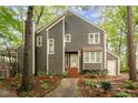 Charming two-story home with gray siding, white trim, and a welcoming front porch surrounded by mature trees at 6035 Sentinel Dr, Raleigh, NC 27609