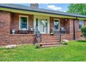 Inviting front entrance with brick steps leading to a cozy porch and chairs at 750 Greenleaf Rd, Angier, NC 27501