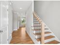 Light-filled entryway with wooden floors, staircase with metal spindles, and an adjacent view to the yard at 7719 Barefoot Rd, Fuquay Varina, NC 27526