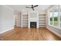 Cozy living room with hardwood floors, a gas fireplace, custom built-ins, and ample natural light at 7719 Barefoot Rd, Fuquay Varina, NC 27526