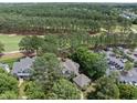 An aerial view of the home surrounded by lush trees, next to a golf course and a parking lot at 1300 Heritage Club Ave, Wake Forest, NC 27587