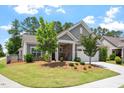 Charming home with a well-manicured lawn and tasteful landscaping, featuring stone accents and a cozy front porch at 1357 Prevenient Dr, Wake Forest, NC 27587