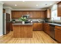 Well-equipped kitchen with stainless steel appliances, central island, wood cabinets, and light hardwood floors at 1833 Creek Oak Circle Cir, Fuquay Varina, NC 27526