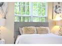 Close-up of bright bedroom showing cozy pillows, a comfortable bed, headboard, and light from a large window at 1912 Parkside Village Dr, Clayton, NC 27520