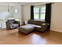 Bright living room with hardwood floors, gray sofas, and a window letting in natural light at 210 Crest Rd, Henderson, NC 27536